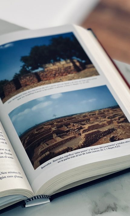 Un libro abierto sobre una mesa, mostrando fotografías e información sobre antiguas ruinas arqueológicas.