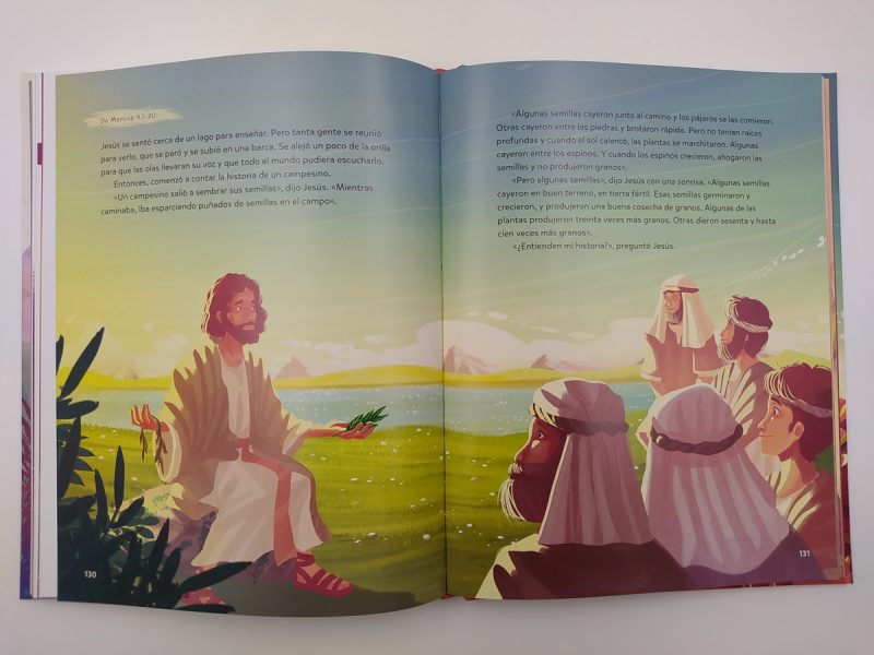 escena luminosa y colorida de una ilustración de libro. En la izquierda, Jesús está sentado cerca de la orilla de un lago, vestido con ropas de la época y delante de un paisaje natural con montañas al fondo. Él extiende sus manos como si estuviera esparciendo semillas mientras enseña una lección. A la derecha, un grupo de cuatro personas lo escucha atentamente. La escena representa la conocida parábola del sembrador de la Biblia y tiene el propósito de educar sobre los distintos resultados del trabajo dependiendo del terreno donde las semillas caigan, un simbolismo que Jesús usaba para describir la recepción de su enseñanza por diferentes tipos de personas. Las páginas del libro incluyen texto en español que complementa la ilustración y ayuda a explicar la narrativa visual.