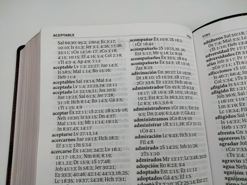 ** Página abierta de un libro de concordancia bíblica, mostrando palabras y referencias de versículos.