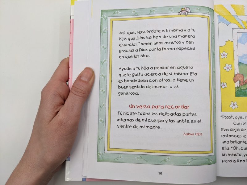 Una mano sosteniendo una página de un libro con texto en español y decoraciones florales, mencionando la gratitud hacia Dios y un verso bíblico del Salmo 13913.