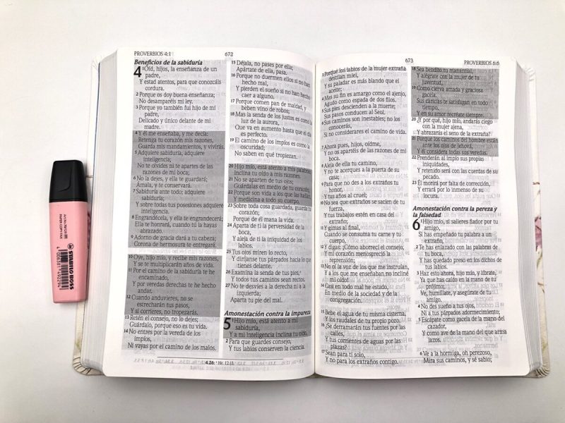 ** Una Biblia abierta en la página de Proverbios, junto a un resaltador rosa.