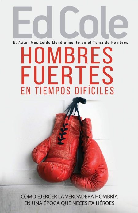 Esta imagen muestra la portada de un libro, con un fondo blanco y guantes de boxeo rojos gastados colgando. La parte superior presenta el nombre del autor Ed Cole en letras grandes seguido por una frase que lo aclama como el autor más leído mundialmente en el tema de hombres. El título principal, destacado en letras rojas grandes, dice HOMBRES FUERTES EN TIEMPOS DIFÍCILES. Debajo de los guantes, aparece un subtítulo que añade profundidad al tema del libro CÓMO EJERCER LA VERDADERA HOMBRÍA EN UNA ÉPOCA QUE NECESITA HÉROES. El diseño sugiere un enfoque en la masculinidad y resiliencia frente a adversidades.