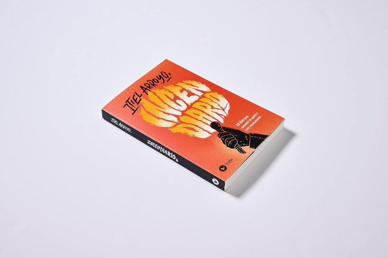 ** "Libro titulado 'Zezowate' con una portada naranja brillante ilustrada con una figura en mano haciendo un gesto."