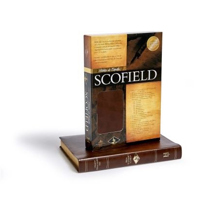 Una Biblia de estudio Scofield colocada sobre un soporte de libro de madera, con el lomo visible y la caja del libro a un lado.