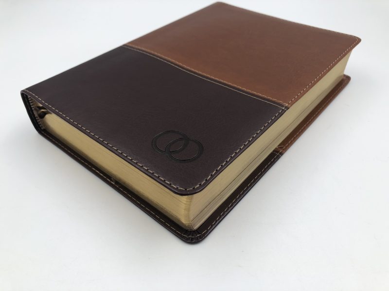 ** Biblia cubierta en cuero marrón oscuro y claro con diseño de bordado.
