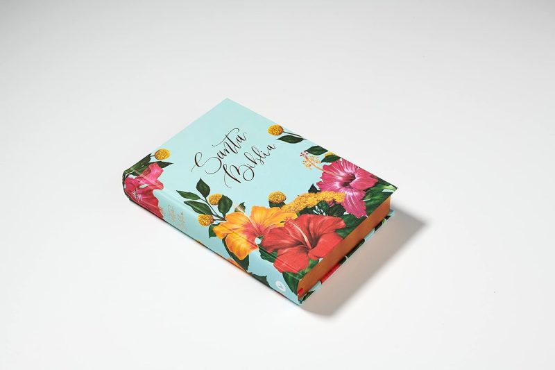 ** Cuaderno con portada de flores tropicales sobre un fondo azul claro.