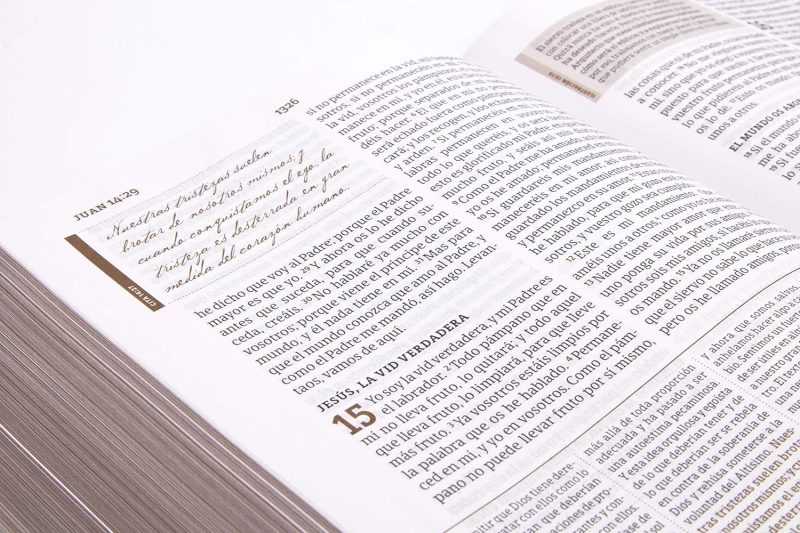 ** Primer plano de una Biblia abierta en el Evangelio de Juan, capítulo 15, con notas manuscritas en el margen.