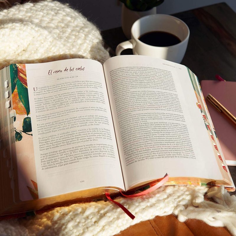 ** Un libro abierto sobre una manta tejida junto a una taza de café.