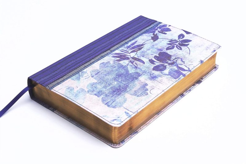 ** Diario con tapa de diseño floral azul y cinta de cierre elástica.