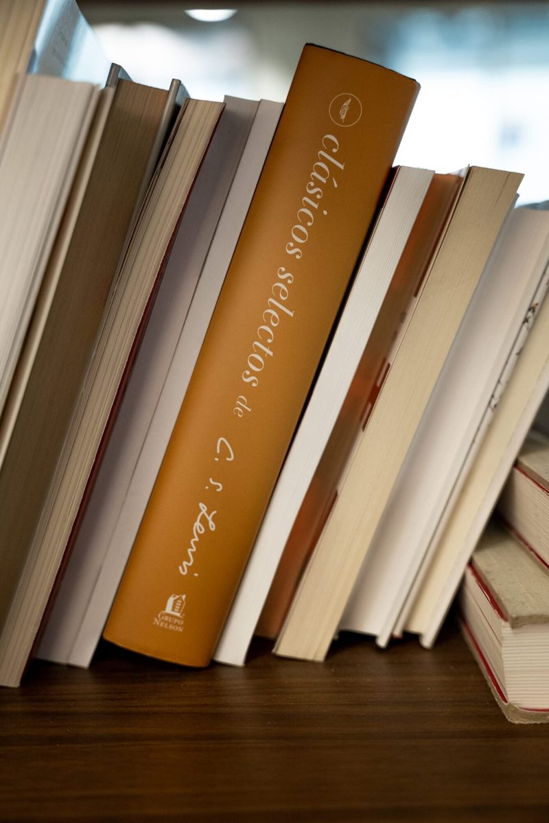 Primer plano de una serie de libros apilados en una estantería con el enfoque en la lomera de un libro marrón titulado 'Clásicos selectos'.