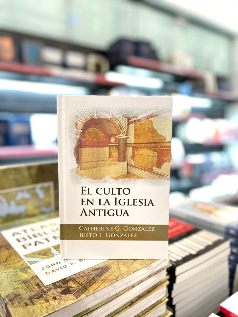 El libro 'El culto en la Iglesia antigua' de Catherine G. González y Justo L. González, en foco sobre un mostrador en una librería con estantes de libros desenfocados en el fondo.