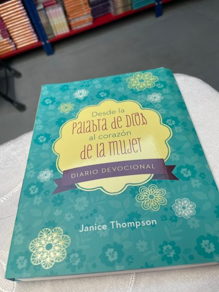 Fotografía de un libro titulado Desde la palabra de Dios al corazón de la mujer por Janice Thompson sobre un fondo desenfocado con estantes de libros.