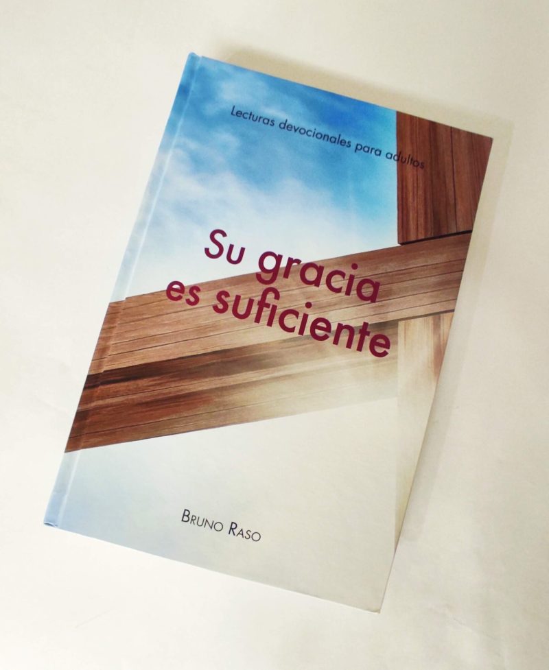 Portada de libro 'Su gracia es suficiente' con fondo de cielo azul y una cruz de madera, implicando contenido espiritual o religioso.