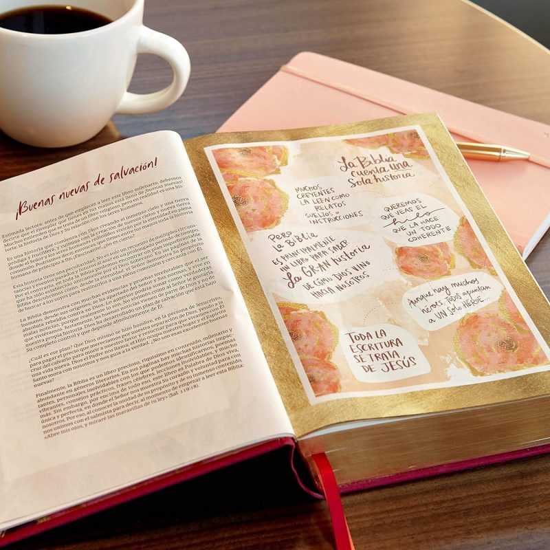 ** Una Biblia abierta en una mesa junto a una taza de café y un cuaderno rosado con un bolígrafo.