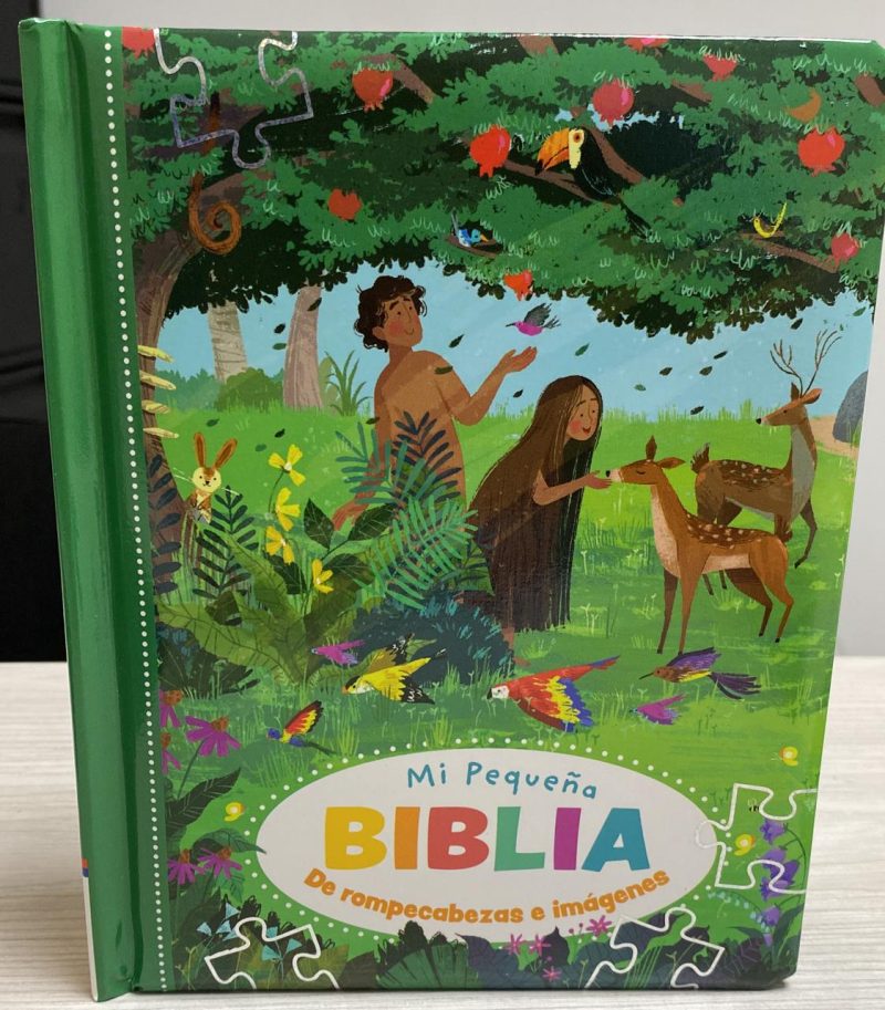 Imagen de la portada del libro Mi Pequeña Biblia, que presenta ilustraciones coloridas de dos figuras humanas rodeadas por animales y naturaleza, con piezas de rompecabezas a lo largo de los bordes.