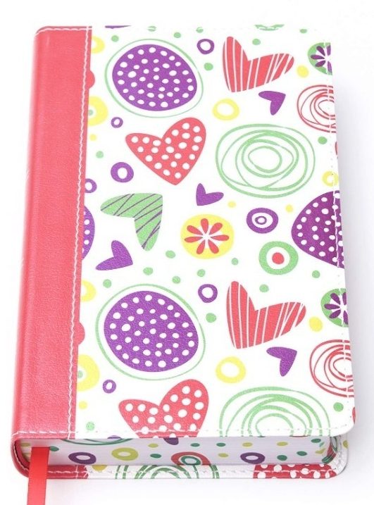 Una agenda con una cubierta blanca estampada con corazones, círculos, y diseños abstractos en colores rojo, morado, verde y amarillo, con el lomo y la banda de cierre en rojo.