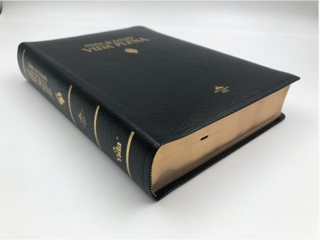 Una Biblia con tapa de cuero negro y detalles dorados en un fondo blanco.