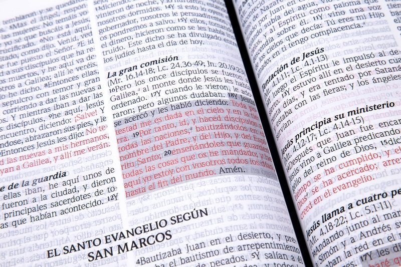 ** Primer plano de una Biblia abierta en el Evangelio de San Marcos, con texto subrayado en rojo.