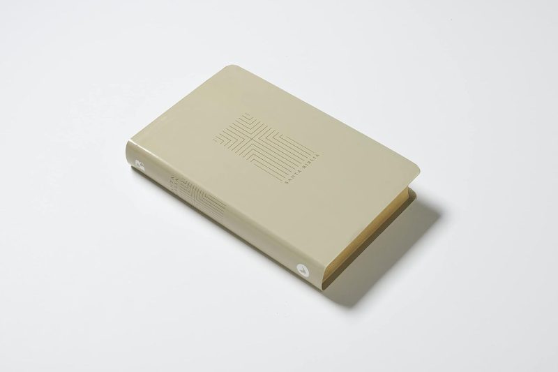 ** Un libro de tapa dura color beige, cerrado y colocado sobre un fondo blanco