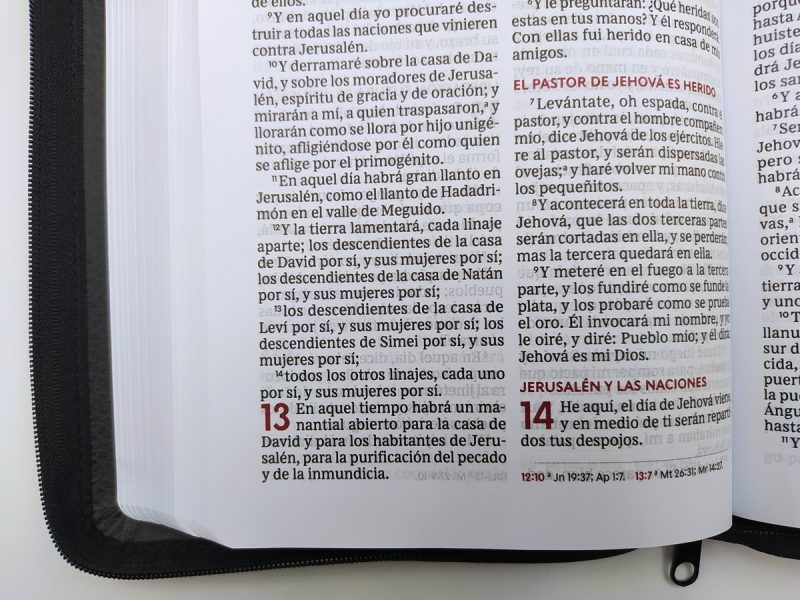 ** Página abierta de una Biblia mostrando el texto de Zacarías 13:1-14 en español, con parte del texto en color rojo.