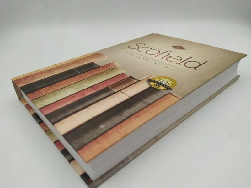 ** Vista en perspectiva de una Biblia Scofield con tapa dura y diseño de estantes de libros.