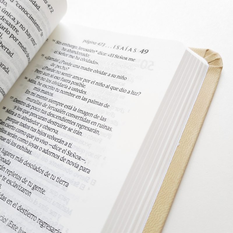 ** Primer plano de una Biblia abierta en la página de Isaías 49, mostrando el texto en español sobre una superficie blanca con esquinas ligeramente dobladas.