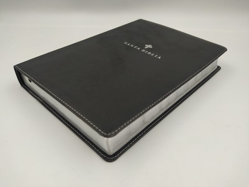 ** Una Biblia de color negro con borde blanco y la inscripción "Santa Biblia" en su cubierta.