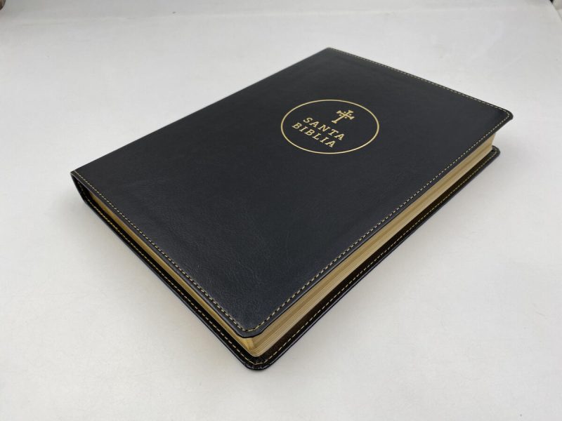 ** Una Biblia de tapa dura con cubierta negra y letras doradas sobre una mesa blanca.