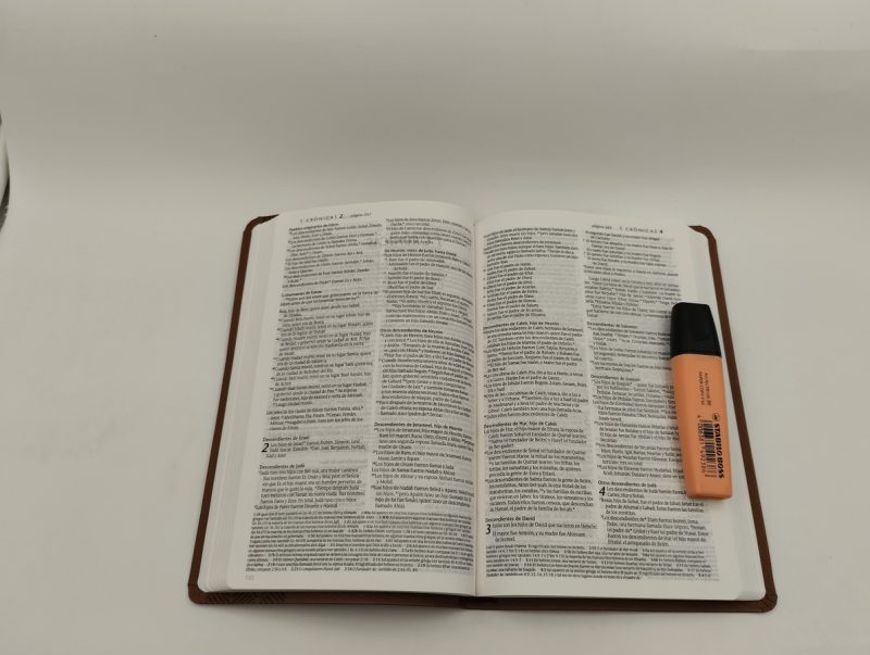 ** Un libro abierto sobre una mesa blanca junto a un marcador naranja.