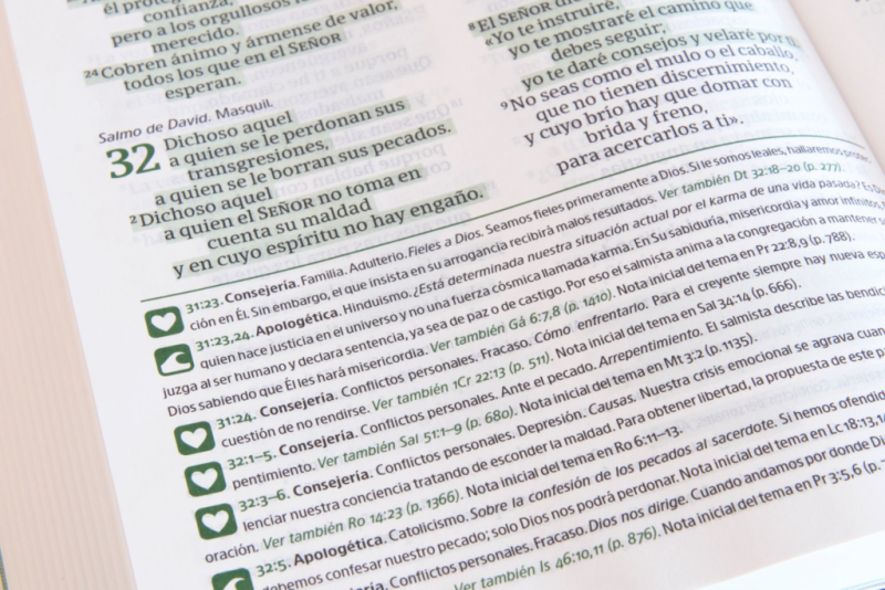 ** Primer plano de una página de texto religioso con varias anotaciones y versículos resaltados en color verde.
