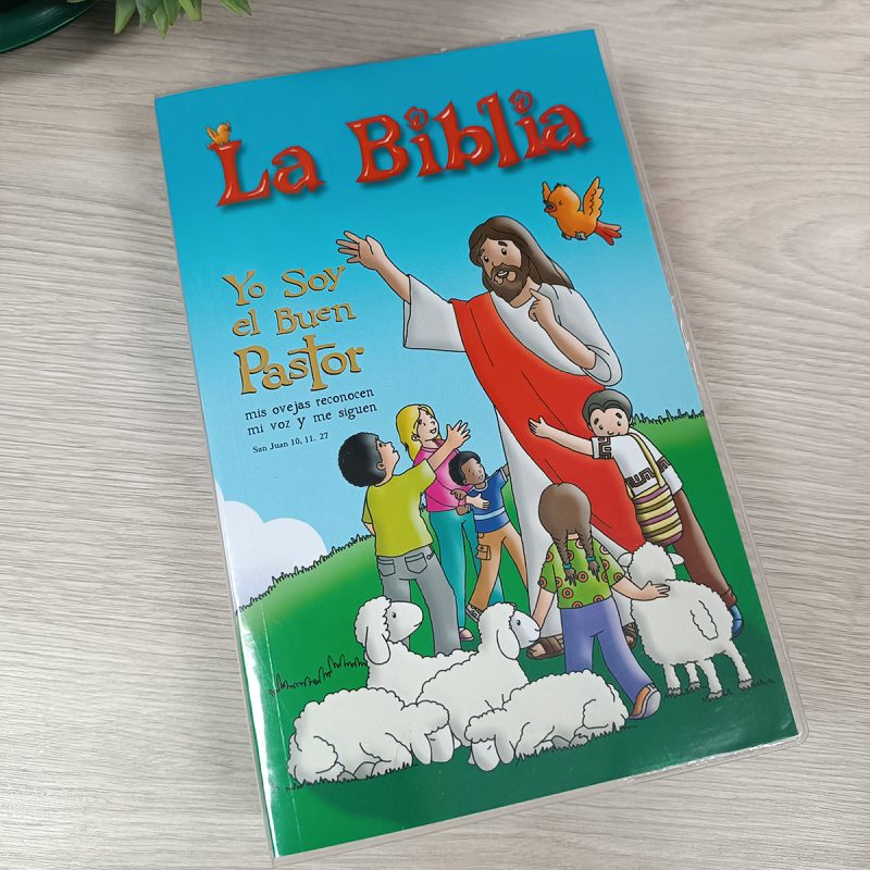** Portada de una edición infantil de la Biblia titulada "La Biblia: Yo Soy el Buen Pastor", con una ilustración de Jesús rodeado de niños y ovejas en un campo verde.