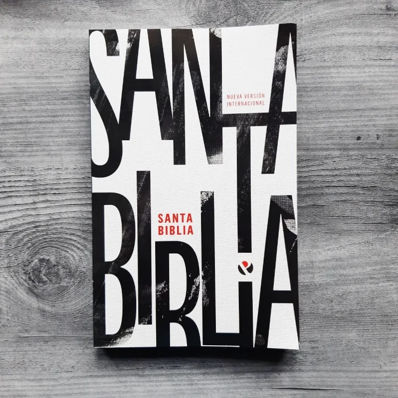** Una biblia con diseño contemporáneo en una portada blanca con letras negras grandes y el texto "Santa Biblia" destacado en rojo.