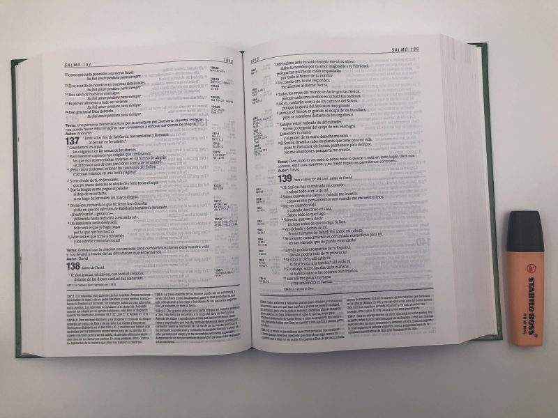 ** Un libro abierto en una mesa blanca junto a un resaltador naranja.