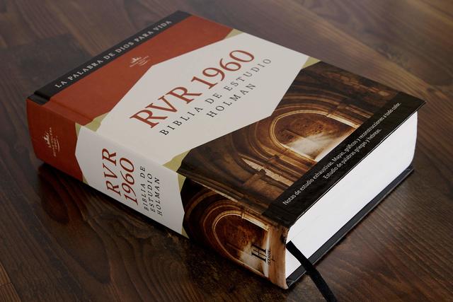 ** Biblia de Estudio RVR 1960 colocada sobre una mesa de madera, mostrando su cubierta con diseño arquitectónico.