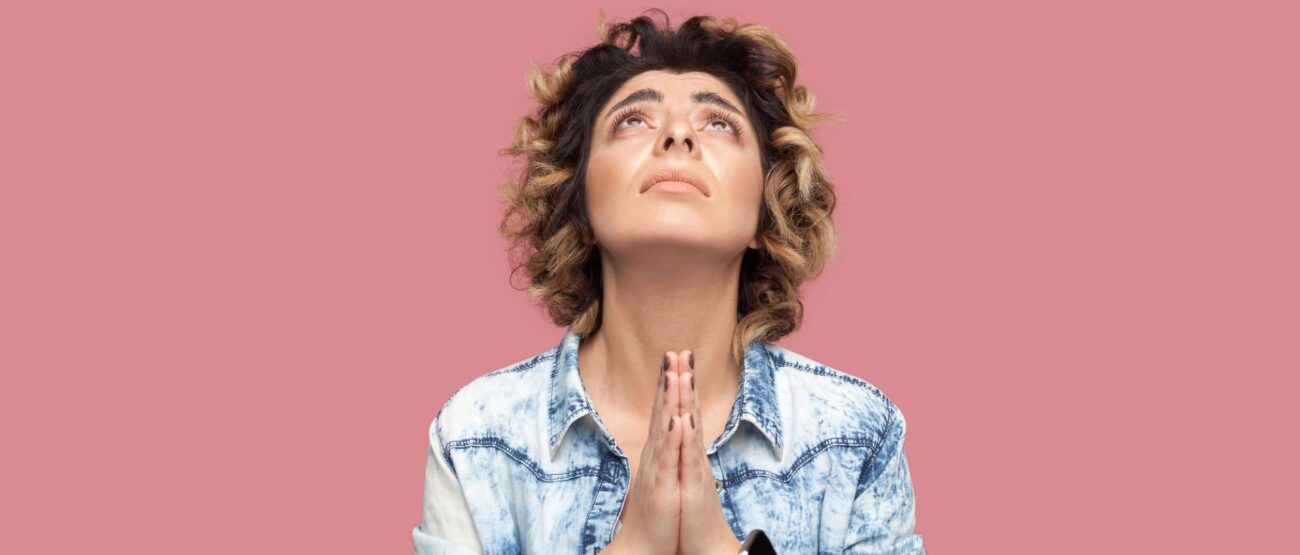 El perdón sin límites: ¿Qué significa “70 veces 7” en la Biblia? 3 Mujer con mirada al cielo y manos juntas en actitud de súplica