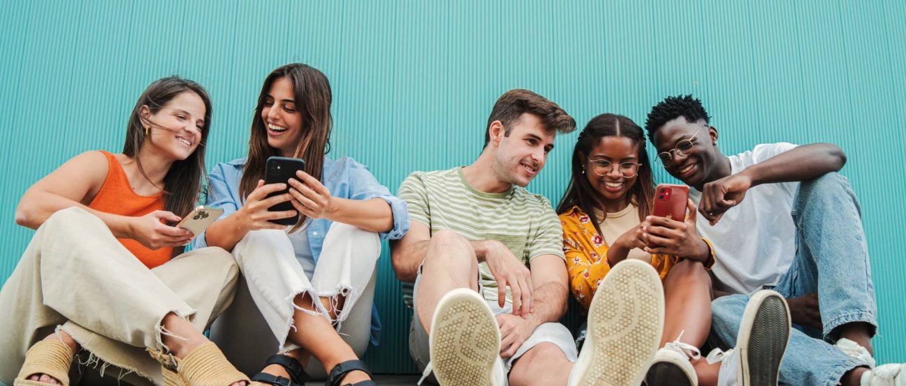 Jóvenes cristianos sonrientes mirando sus teléfonos mientras comparten versículos bíblicos