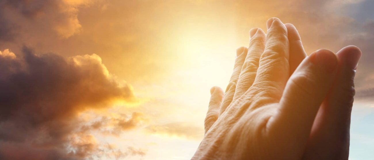 Manos elevadas en oración al amanecer