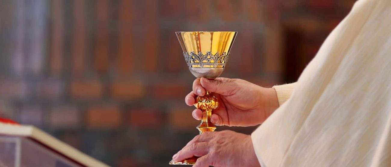 Sacerdote celebrando misa en una iglesia antigua iluminada por una ventana circular.