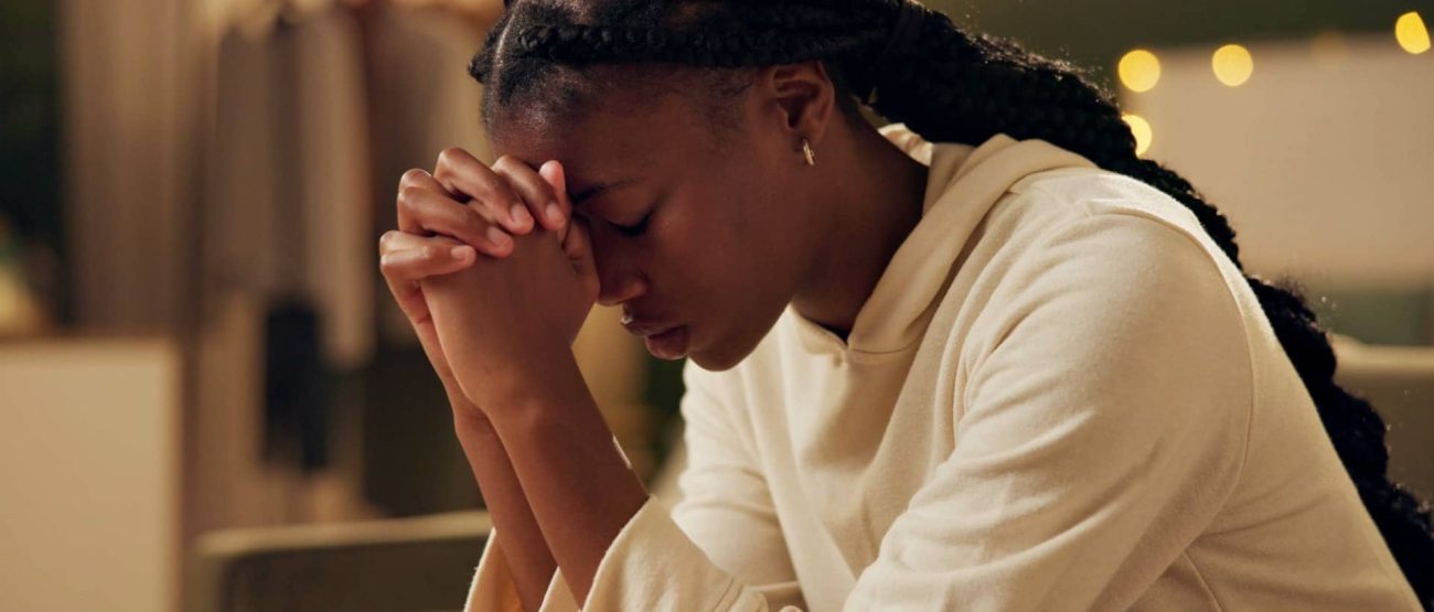 Mujer con trenzas orando con las manos juntas en actitud de recogimiento